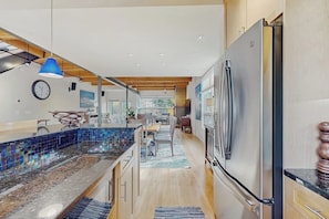 Eine moderne Küche mit einem großen Kühlschrank, Holzbalkendecke und einer blauen Pendelleuchte.