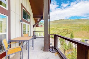 Ein Balkon mit Tisch und Stühlen, mit Blick auf eine grüne Landschaft.