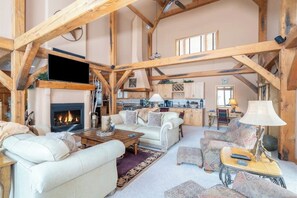 A spacious living area with a fireplace, sofas, and a kitchen in the background. - Two-story, dog-friendly home with fireplace & W/D (Mountain Village)