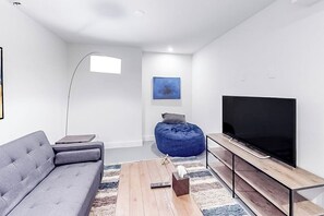 A modern living room with a grey sofa, a wooden coffee table, a blue bean bag, a flat-screen TV, and a floor lamp. - Dog-friendly home close to Telluride with W/D, balcony & yard (Mountain Village)