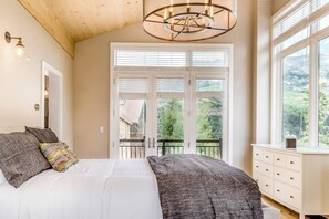 A bedroom with a large bed, a dresser, and a view of a balcony. - Dog-friendly home close to Telluride with W/D, balcony & yard (Mountain Village)