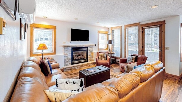 A living room with a fireplace, leather sofa, and a television. - TL1112 | Mountain Condo | Pool | Hot Tubs | Winter Shuttles (Steamboat Springs)