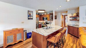 A kitchen with a central island, wooden cabinets, and a bar area with stools. - TL1112 | Mountain Condo | Pool | Hot Tubs | Winter Shuttles (Steamboat Springs)
