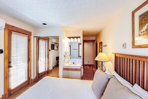 Ein Hotelzimmer mit Bett, einem Badezimmer mit Waschbecken und Spiegel sowie einem Flur, der zu einem weiteren Zimmer führt.