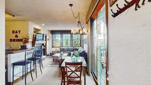 Una cuina moderna amb una zona de bar, una taula de menjador amb caires, un sofà i una finestra gran amb vistes.