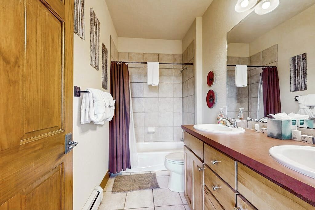 A bathroom with a wooden door, a bathtub, a toilet, a sink, and a mirror.
