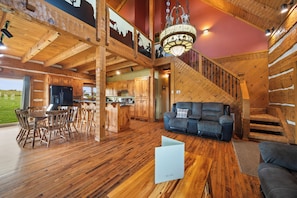A spacious interior with wooden floors, a dining area, a living room with a sofa, and a staircase.