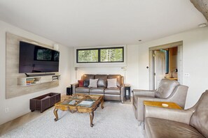Ein modernes Wohnzimmer mit einer Ledersofa, einem Glastisch und einem an der Wand befestigten Flachbildfernseher.