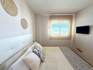 Un dormitorio con cama, ventana, televisor de pared y decoración en la pared.