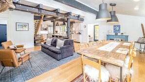 Una sala de estar moderna con un sofá, sillas, una mesa de comedor y una escalera que sube a una cocina.