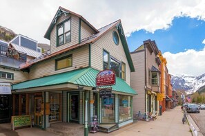 A two-story building with a green awning, a sign for 'Andrews Real Estate,' and a storefront for 'Bell Bent Leather Silver.'