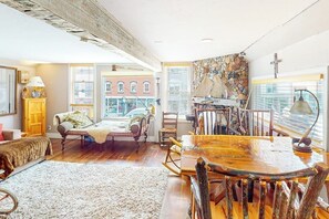 A spacious living room with a large wooden dining table, a cozy sofa, and a fireplace.
