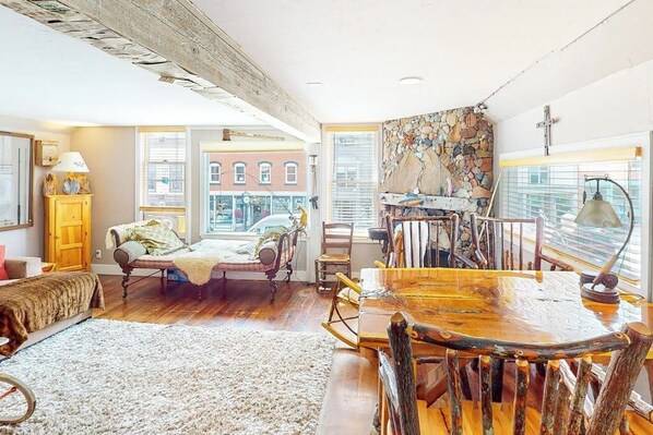 A spacious living room with a large wooden dining table, a cozy sofa, and a fireplace.