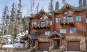 A multi-story log cabin with balconies, stone foundation, and a garage. - Gorgeous mountain home with balcony, fireplace & views (Mountain Village)