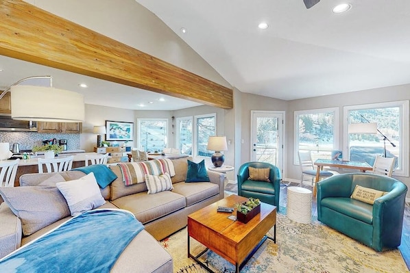 A spacious living area with a wooden ceiling, a sofa set, a coffee table, and a dining area with a table and chairs. - Four-story home with amazing mountain/golf view, fireplace & Ping-Pong (Avon)