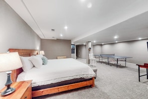 A bedroom with a bed, bedside table, lamp, and a ping pong table. - Four-story home with amazing mountain/golf view, fireplace & Ping-Pong (Avon)