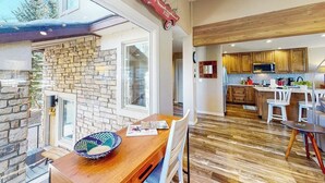 Una cucina moderna con mobili in legno, una parete in pietra e un'area pranzo con tavolo e sedie in legno.