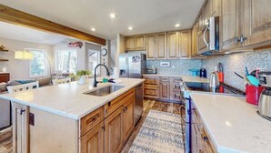 Una cucina moderna con mobili in legno, una grande isola, elettrodomestici in acciaio inossidabile e una parete rivestita di piastrelle.