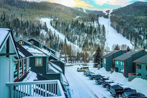 Ein Wohngebiet mit Häusern, einer verschneiten Straße und einem Ski-Hang im Hintergrund.