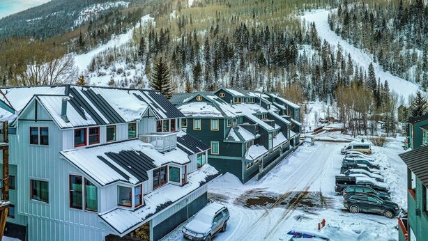 Ett bostadsområde med hus, en snötäckt väg och en skidbacke i bakgrunden.
