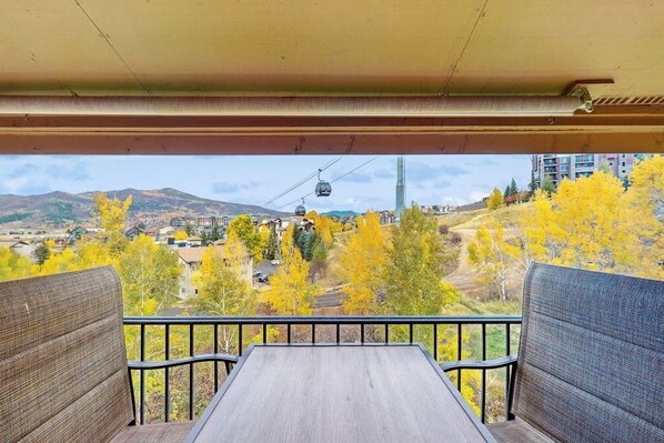 Ein Balkon mit Blick auf eine Berglandschaft, eine Seilbahn und Herbstlaub.