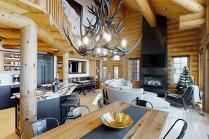 Ein Blockhaus-Interieur mit Essbereich, Küche, Wohnzimmer und Kamin.