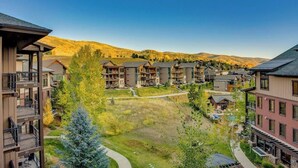 Ett bostadsområde med flerfamiljshus, en grön innergård och en bergskedja i bakgrunden.