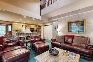 Ein geräumiges Wohnzimmer mit Ledersofas, einem Couchtisch und einem Essbereich mit Tisch und Stühlen.