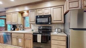 Una cocina con gabinetes de madera, un refrigerador de acero inoxidable, un microondas, un horno y un lavavajillas.