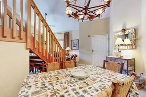 A dining area with a table set for four, a wooden staircase, and a chandelier. - Riverfront gem with loft & stunning water views, near skiing (Edwards)