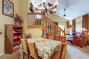 A dining area with a wooden table and chairs, a staircase, a sofa, and a chandelier. - Riverfront gem with loft & stunning water views, near skiing (Edwards)