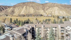 A residential area with apartment buildings, a parking lot, and a mountainous backdrop. - Beaver Creek West Condo with Heated Pool, 3 Hot Tubs & Shuttle to the Slopes (Avon)