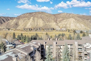 Zona residencial con edificios de apartamentos, un estacionamiento y montañas al fondo.