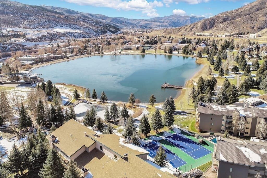A lake surrounded by buildings, trees, and mountains.