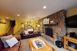 A living room with a stone fireplace, a television, and a sofa. - Beaver Creek West Condo with Heated Pool, 3 Hot Tubs & Shuttle to the Slopes (Avon)