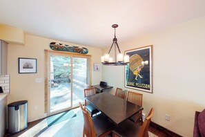 A dining area with a table, chairs, a chandelier, and a poster on the wall. - Spacious Townhome with Hot Tub, Adjacent to Gore Creek | 4.5 Miles to Vail (Vail)