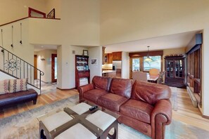 Ein geräumiges Wohnzimmer mit Ledersofa, Couchtisch, Treppe und Essbereich.