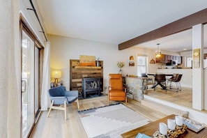 A living room with a fireplace, a dining area with a table and chairs, and a kitchen in the background. - Golf Course Condo with Gas Fireplace, WiFi & Deck with Mountain Views (Avon)