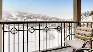 En balkon med udsigt over et sneklædt landskab og en stol.