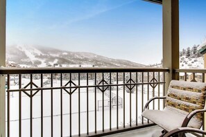 Ein Balkon mit Blick auf eine verschneite Landschaft und einem Stuhl.