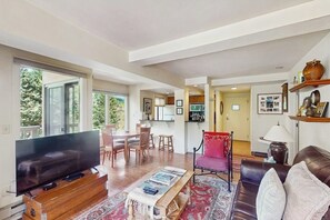 Ein Wohnzimmer mit Fernseher, Couchtisch aus Holz, einem roten Sessel und einer Couch.