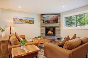 Ein Wohnzimmer mit Kamin, einer Couch, einem Esstisch und Kunstwerken an den Wänden.