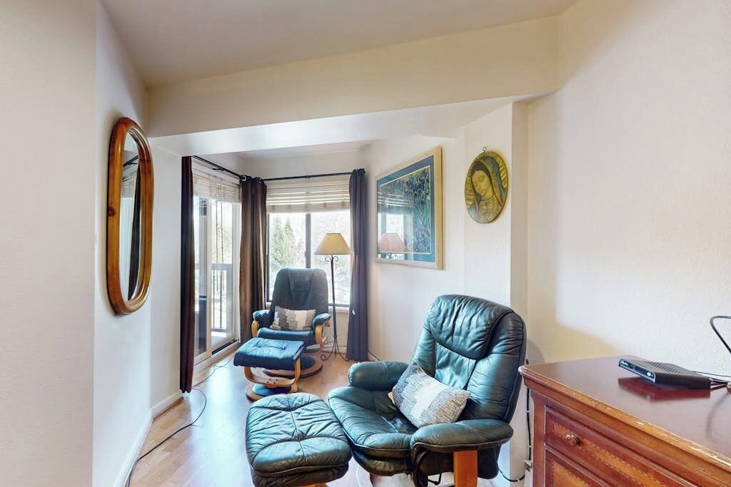 Een woonkamer met een leren bank, een houten kast en een lamp.
