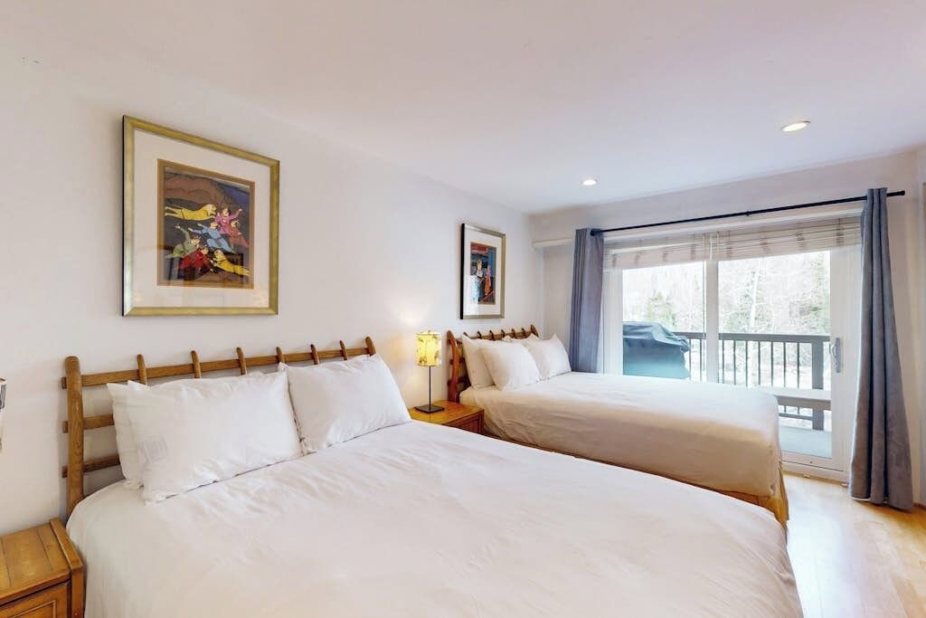 Een hotelkamer met twee bedden, een balkon en een ingelijste foto aan de muur.