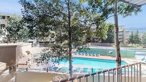 A pool area with lounge chairs, a tennis court, and a building with balconies. - Comfy condo w/hot tub, pool & sauna access- free shuttle to slopes, walk to lake (Avon)