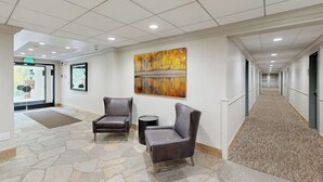 A hallway with two leather chairs, a stone floor, a painting on the wall, and a carpeted area. - Inviting condo with large terrace, pool & hot tub - next to golf/Nordic skiing (Vail)