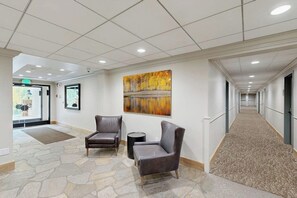 A hallway with two leather chairs, a stone floor, a painting on the wall, and a carpeted area. - Inviting condo with large terrace, pool & hot tub - next to golf/Nordic skiing (Vail)