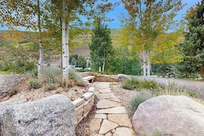 A stone pathway leading through a landscaped area with trees and a view of a hilly landscape. - Fallridge #416 condo with morning-view terrace and game room access (Vail)