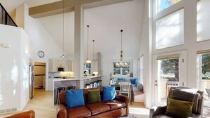 A spacious living area with a leather sofa, a coffee table, and a dining area with a kitchen in the background. - Springs of Arrowhead Getaway w/ Deck, Pool, Hot Tub & Village Shuttle (Edwards)
