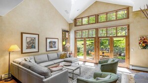 Un vaste salon doté d’un haut plafond, de grandes fenêtres et offrant une vue sur l’extérieur.